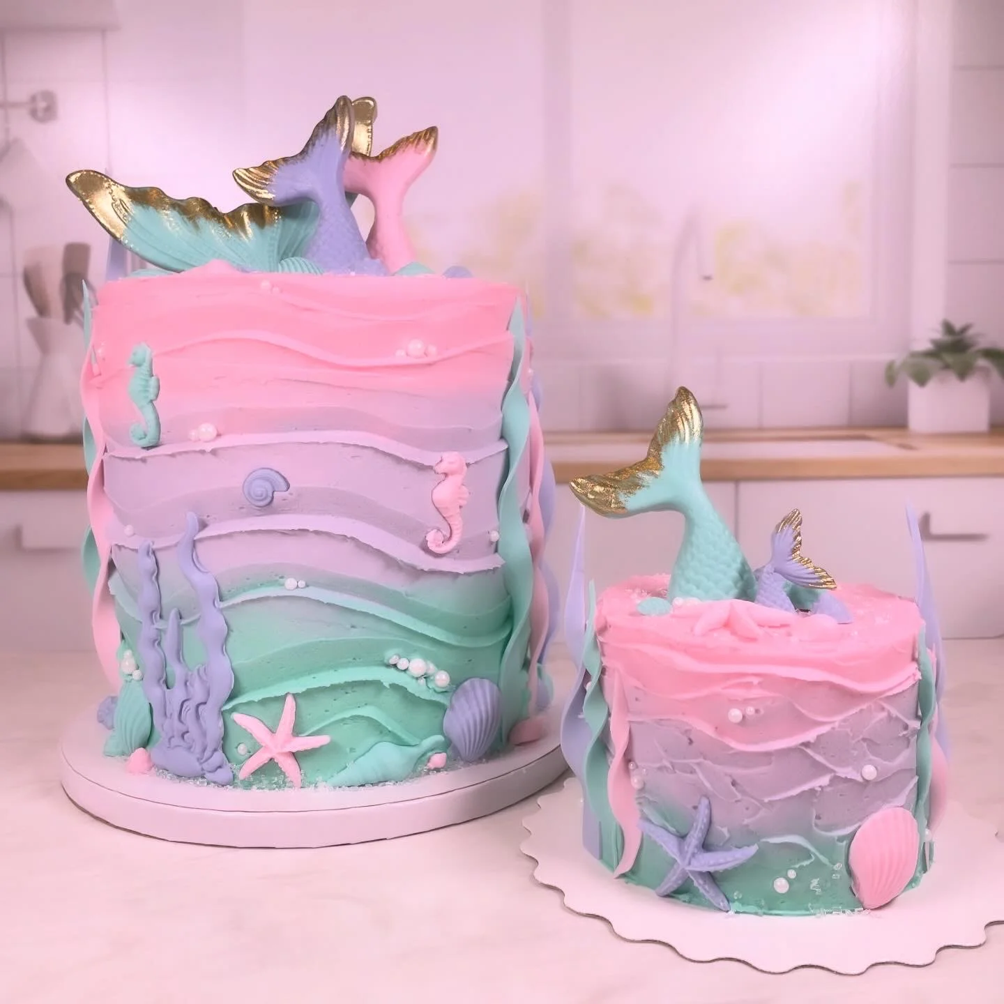 Pastel mermaid themed cakes with seahorses, shells, and gold-tipped tails