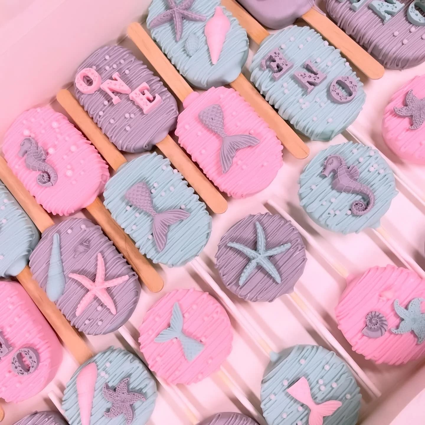 Mermaid themed cake pops with starfish, seahorses, and mermaid tails for first birthday