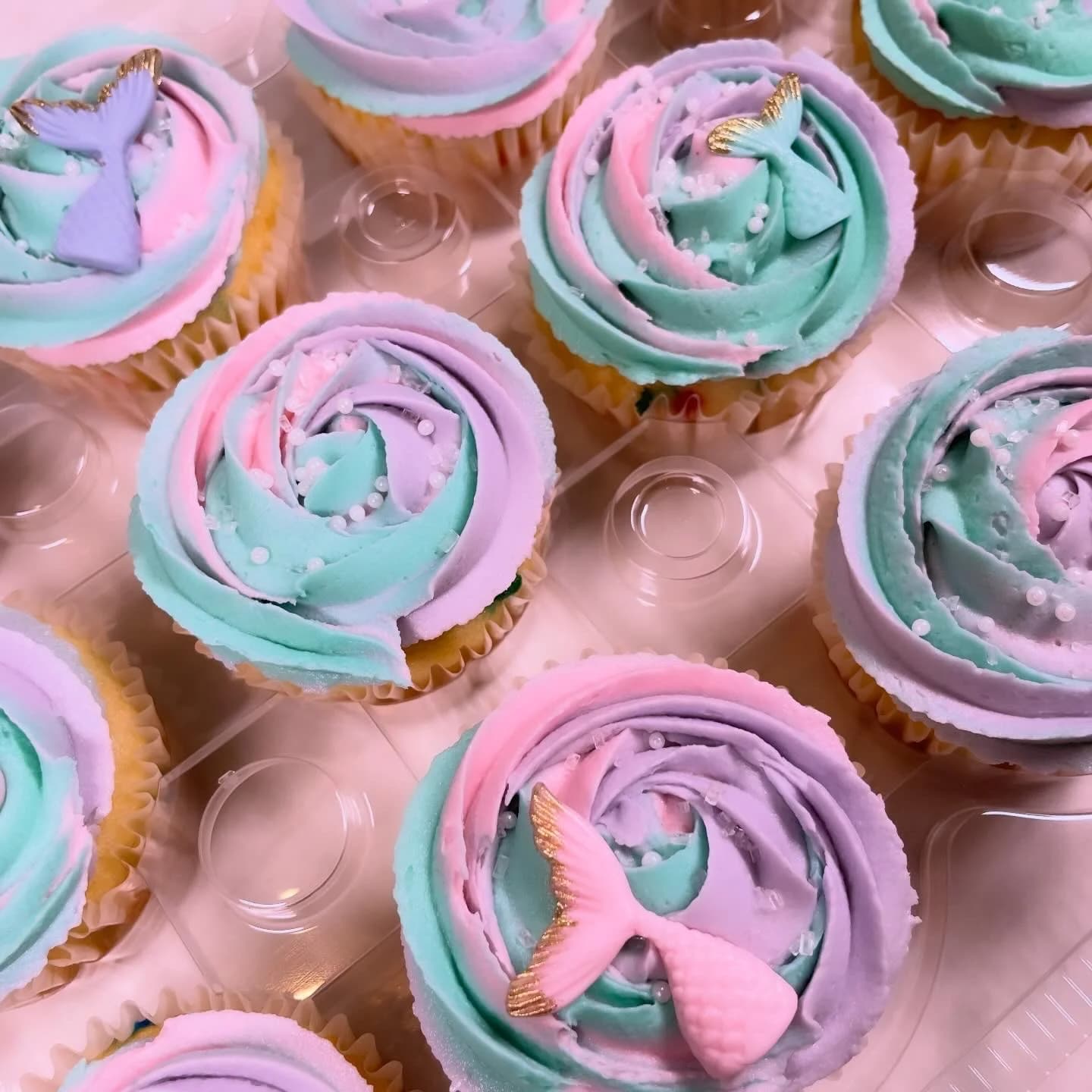 Mermaid-themed cupcakes with pastel pink, purple, and teal swirl frosting